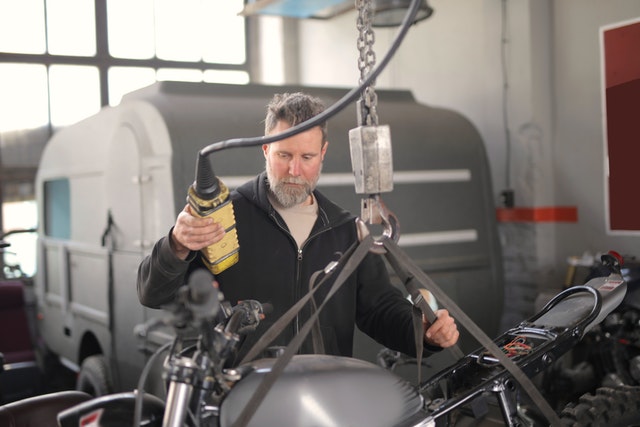 man loading motorcycle on overhead crane
